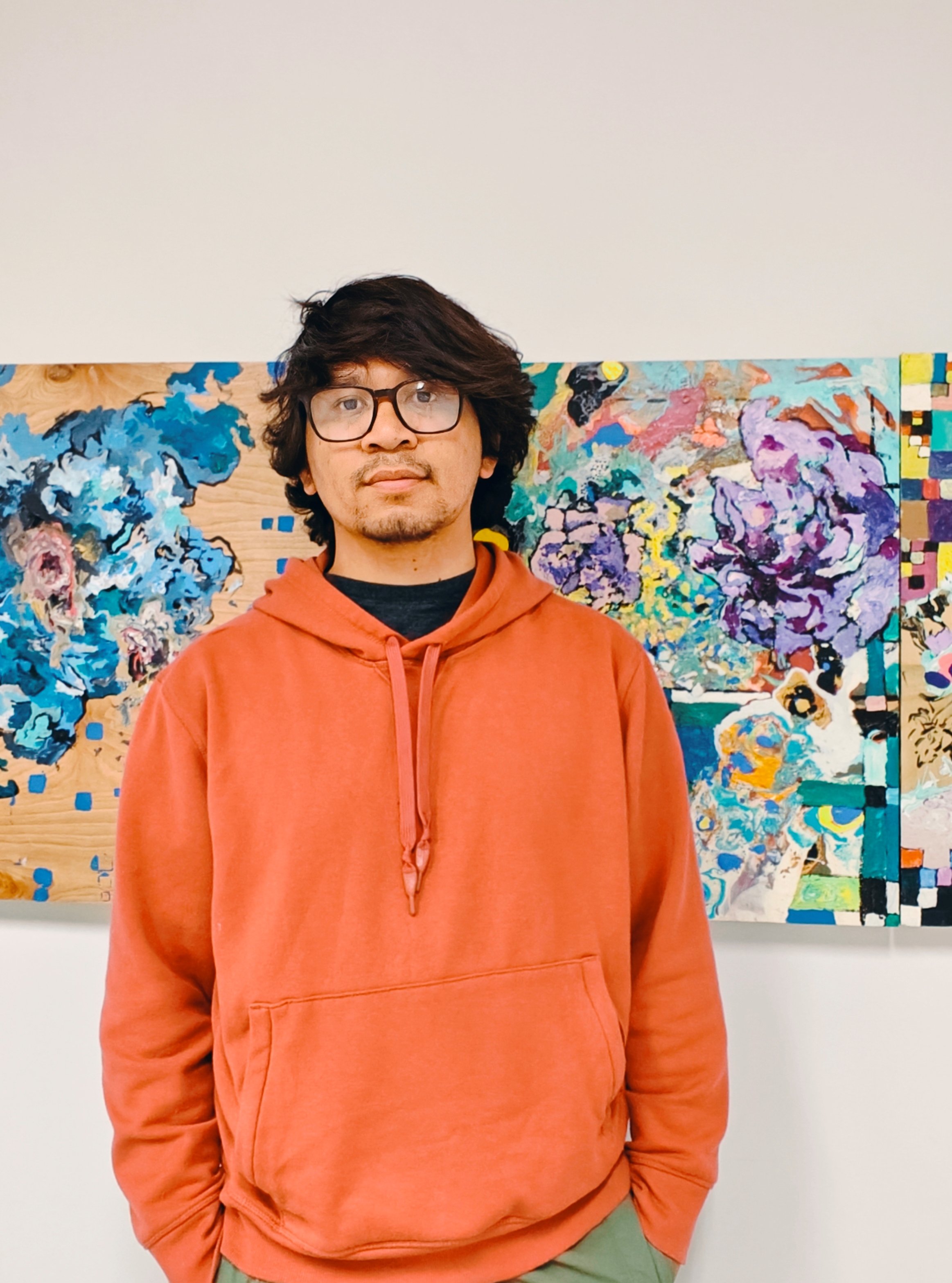 Sokthea who stands in front of his painting on woodpanel.