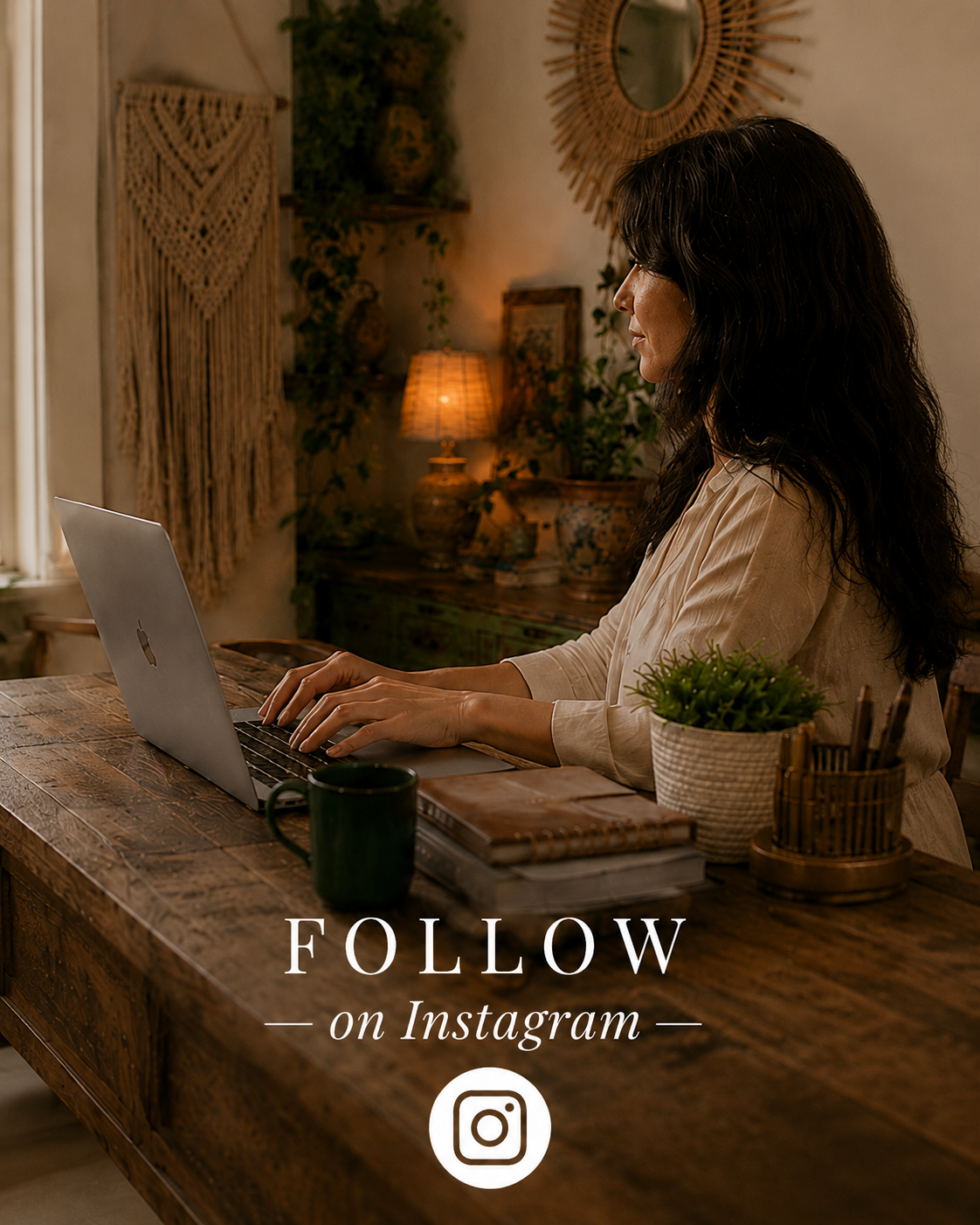 A woman sitting at a rustic wooden desk working on a laptop in a cozy, warmly lit room with decorative wall art, plants, and a lamp.