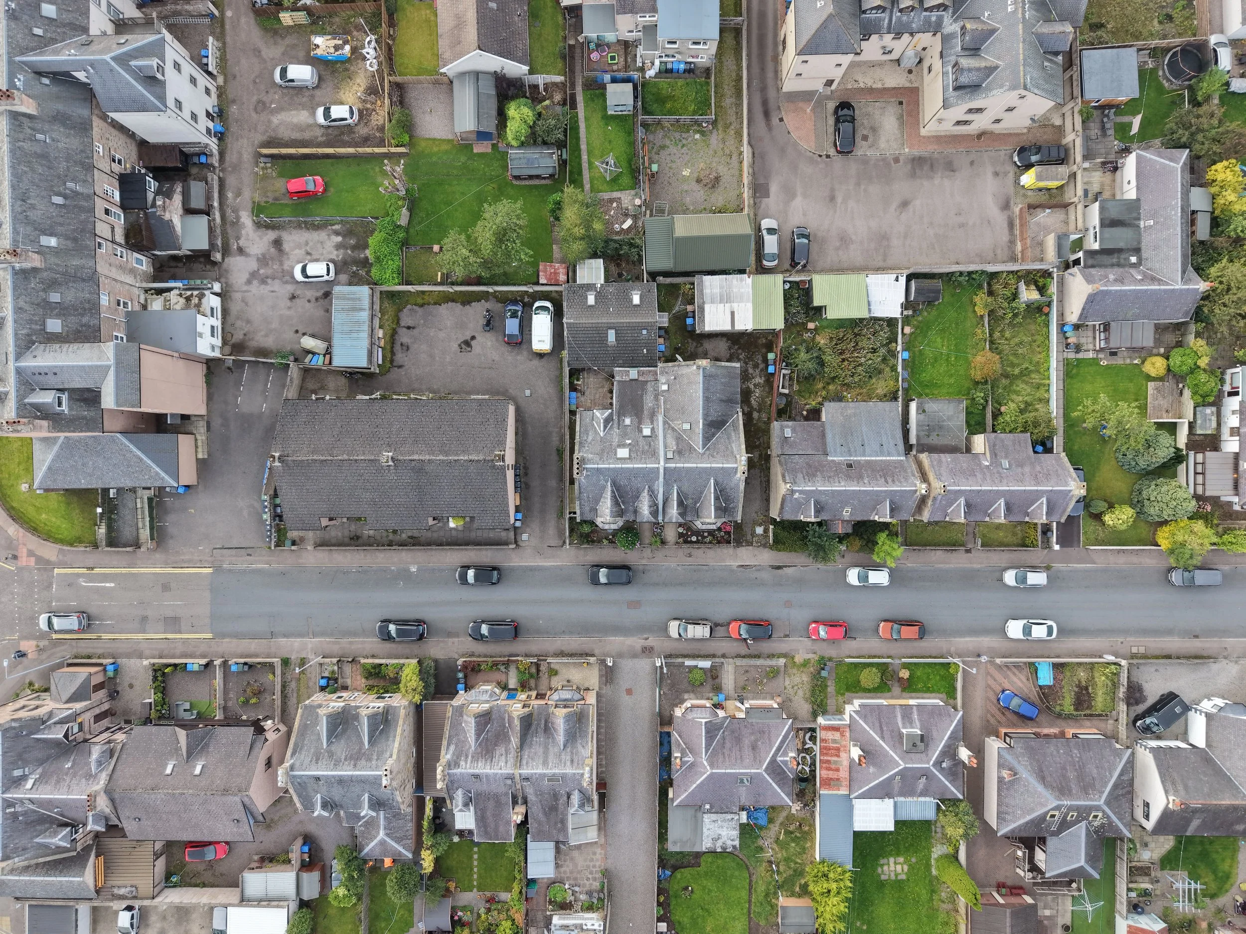 Captured from directly overhead, this aerial perspective zeroes in on Lochalsh Road as it cuts through the established neighbourhoods of western Inverness. The clean linear path of the street is clearly visible, flanked by local housing blocks and gr