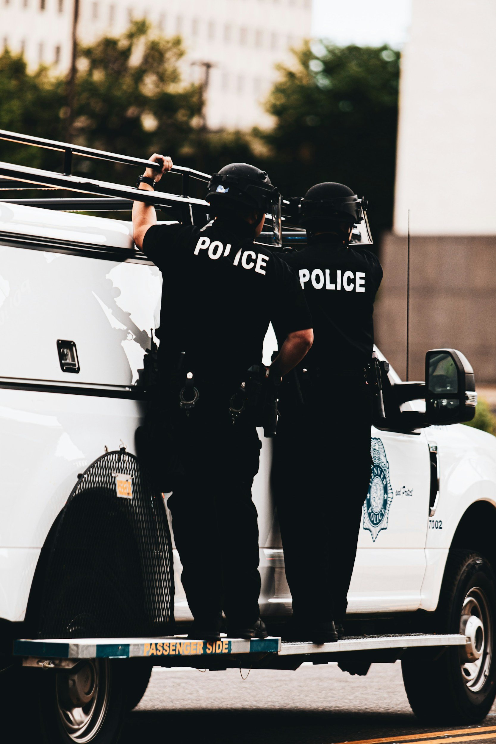 Police officers in tactical uniforms and helmets training beside a patrol vehicle
