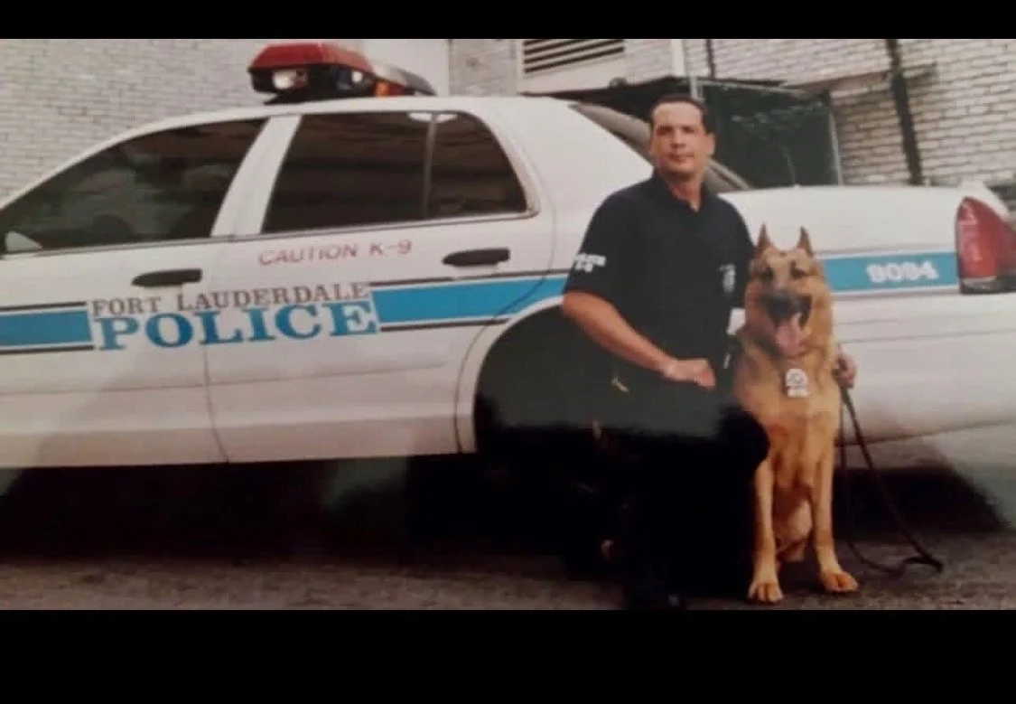 Rich Rodriguez as a K9 officer with his police dog beside a patrol car