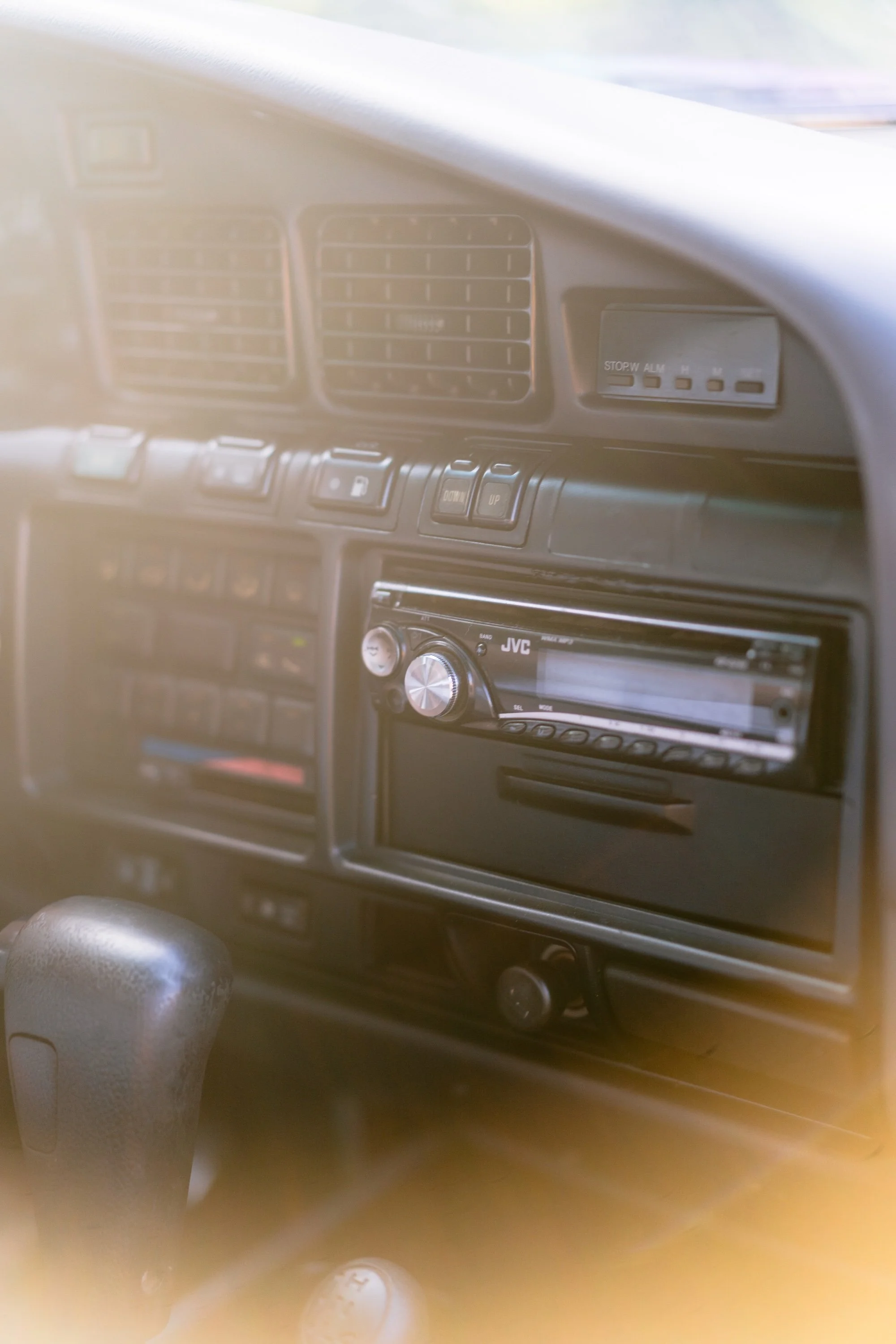 Interior of a vehicle dashboard featuring air vents, a digital clock, a stereo system, and various controls.