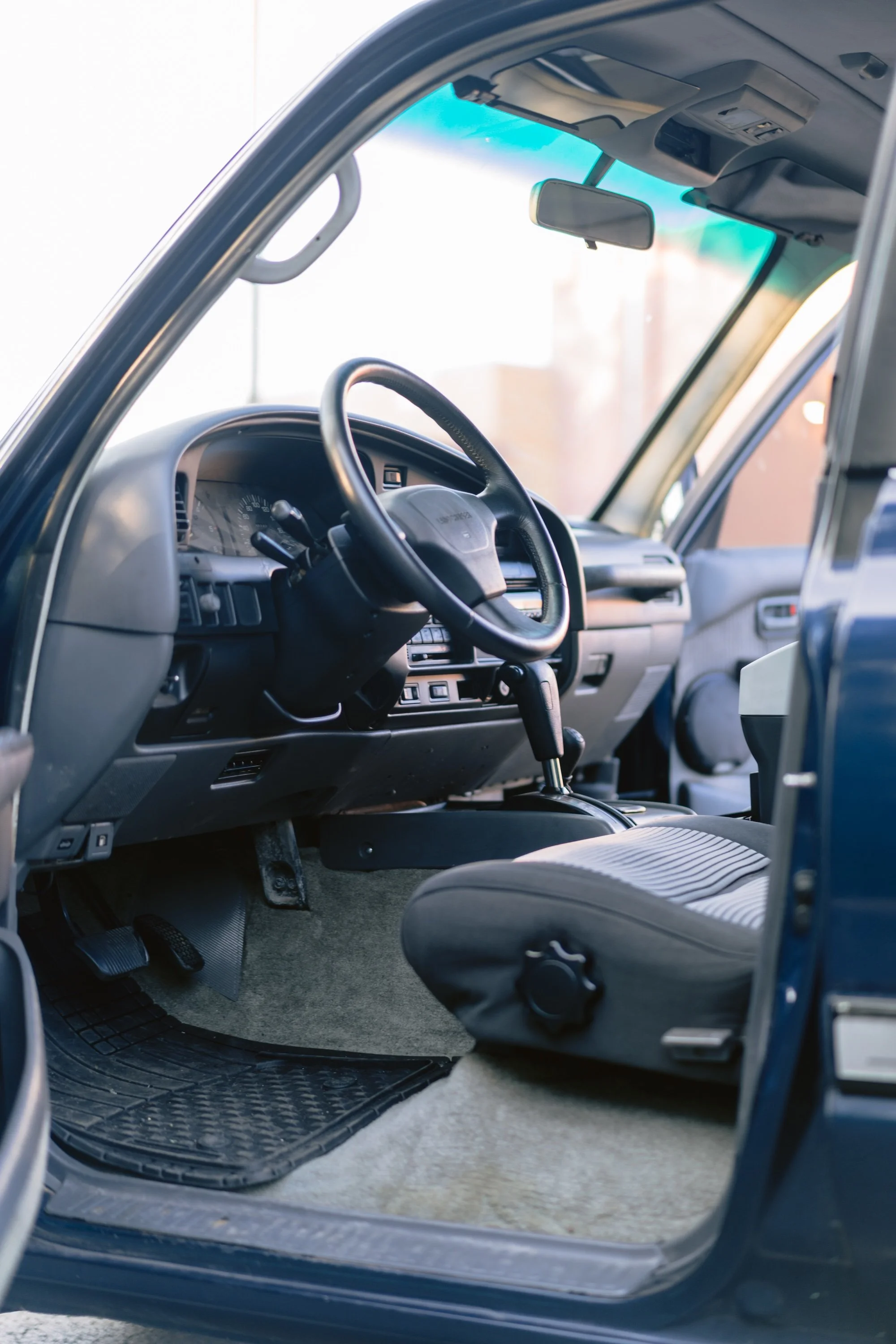 Interior of a vehicle showing the dashboard, steering wheel, driver's seat, and the pedals.
