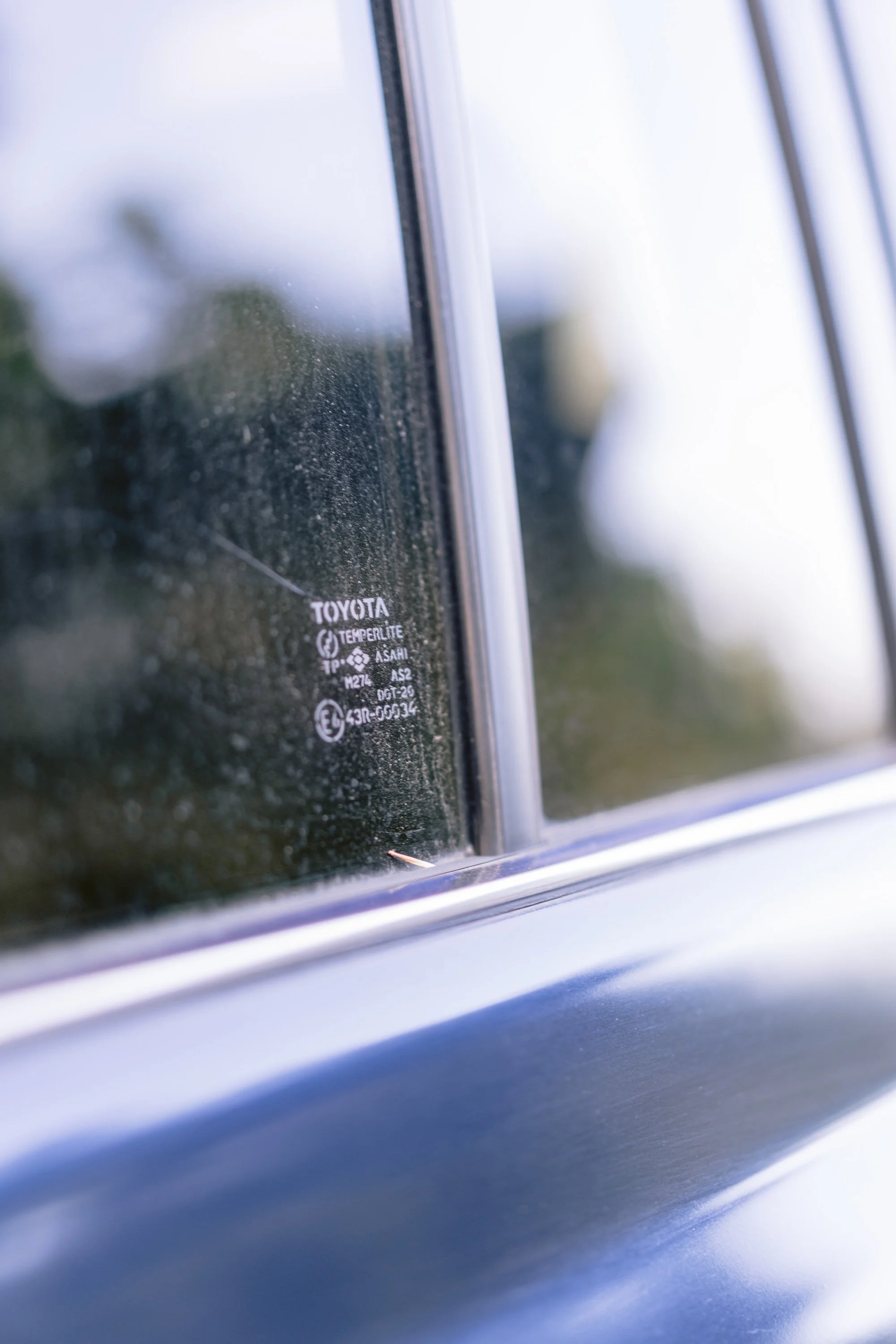 Close-up of a car window with condensation and a logo that reads "Toyota" and similar text, with a blurred background.