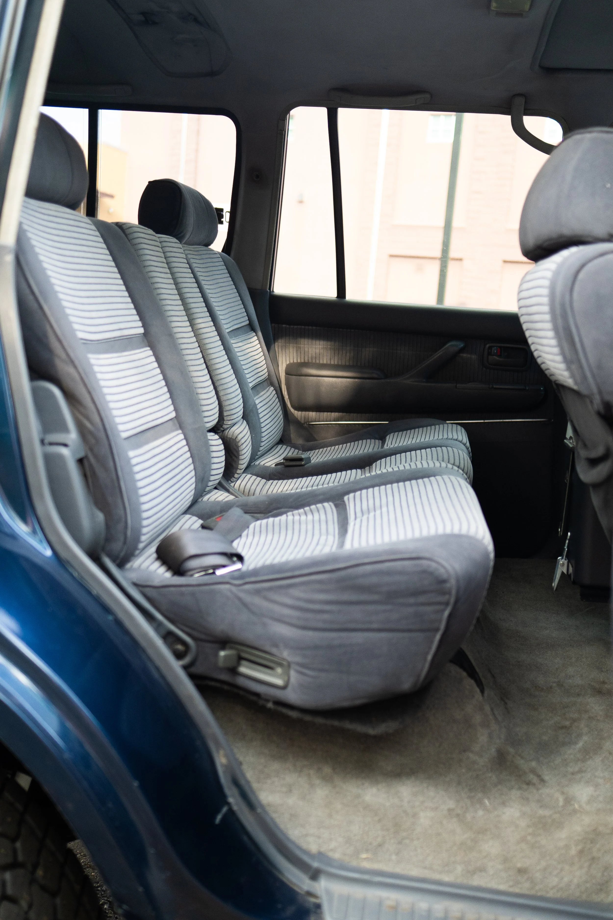 Interior of a vehicle showing striped fabric seats and a gray door panel with a window.