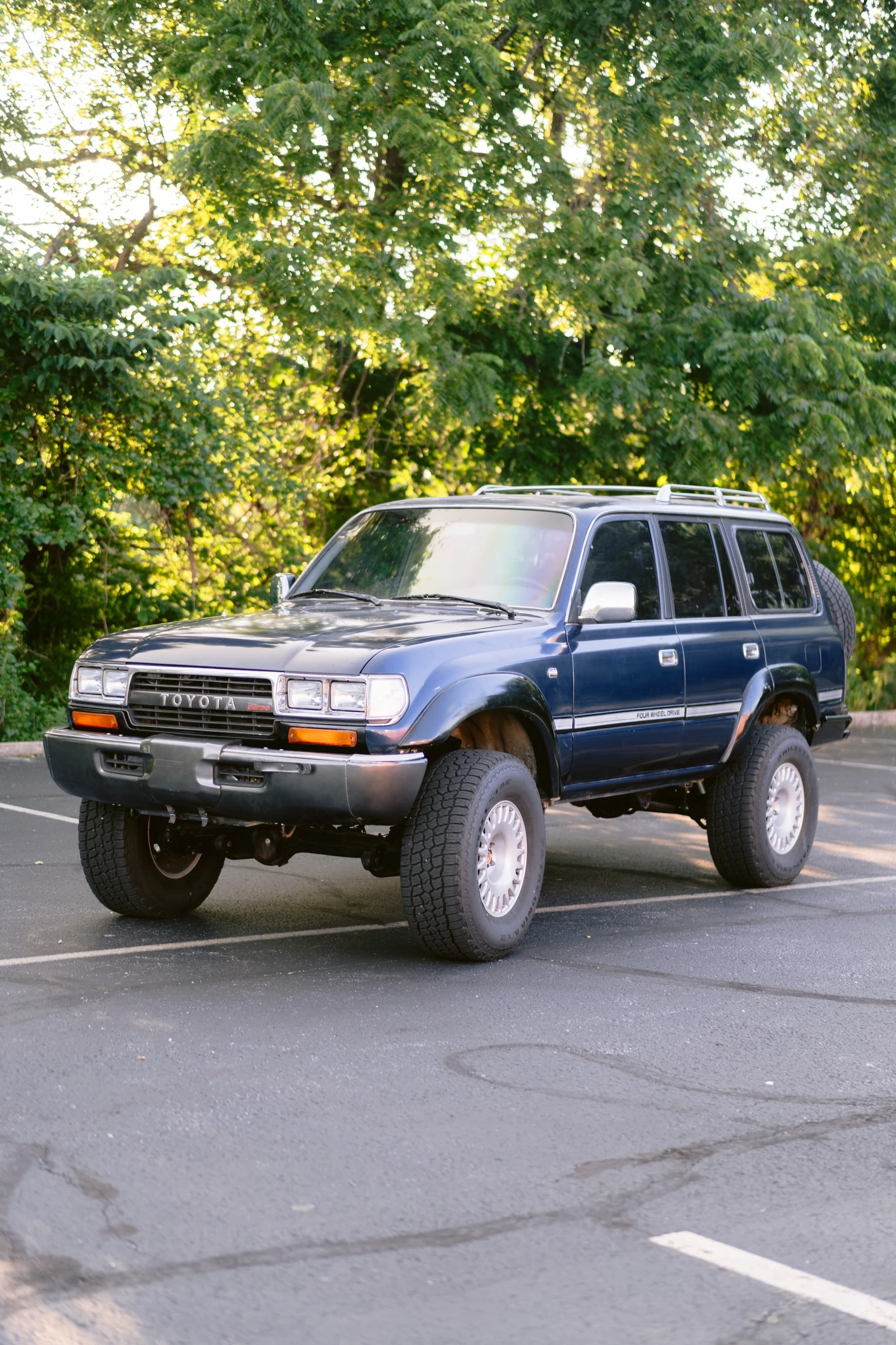 A blue Toyota SUV parked in a parking lot with green trees in the background.