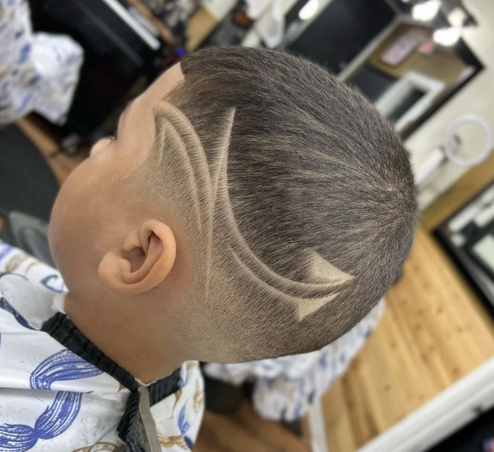 Boy with a haircut featuring a Batman logo shaved into the side of his head.