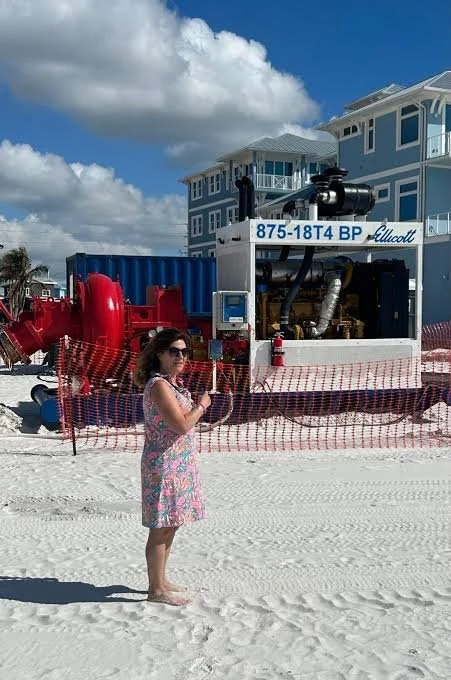 Beach renourishment project on Fort Myers Beach, with a bright blue sky and clouds overhead.