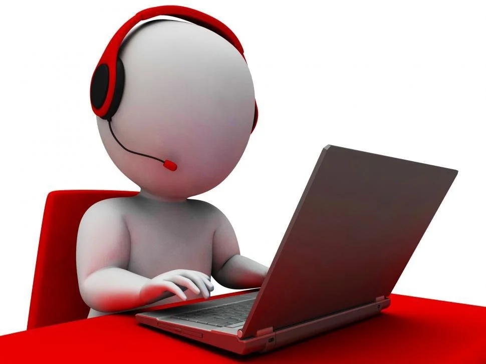 A 3D humanoid figure sitting at a red desk wearing a black and red headset, typing on a laptop.