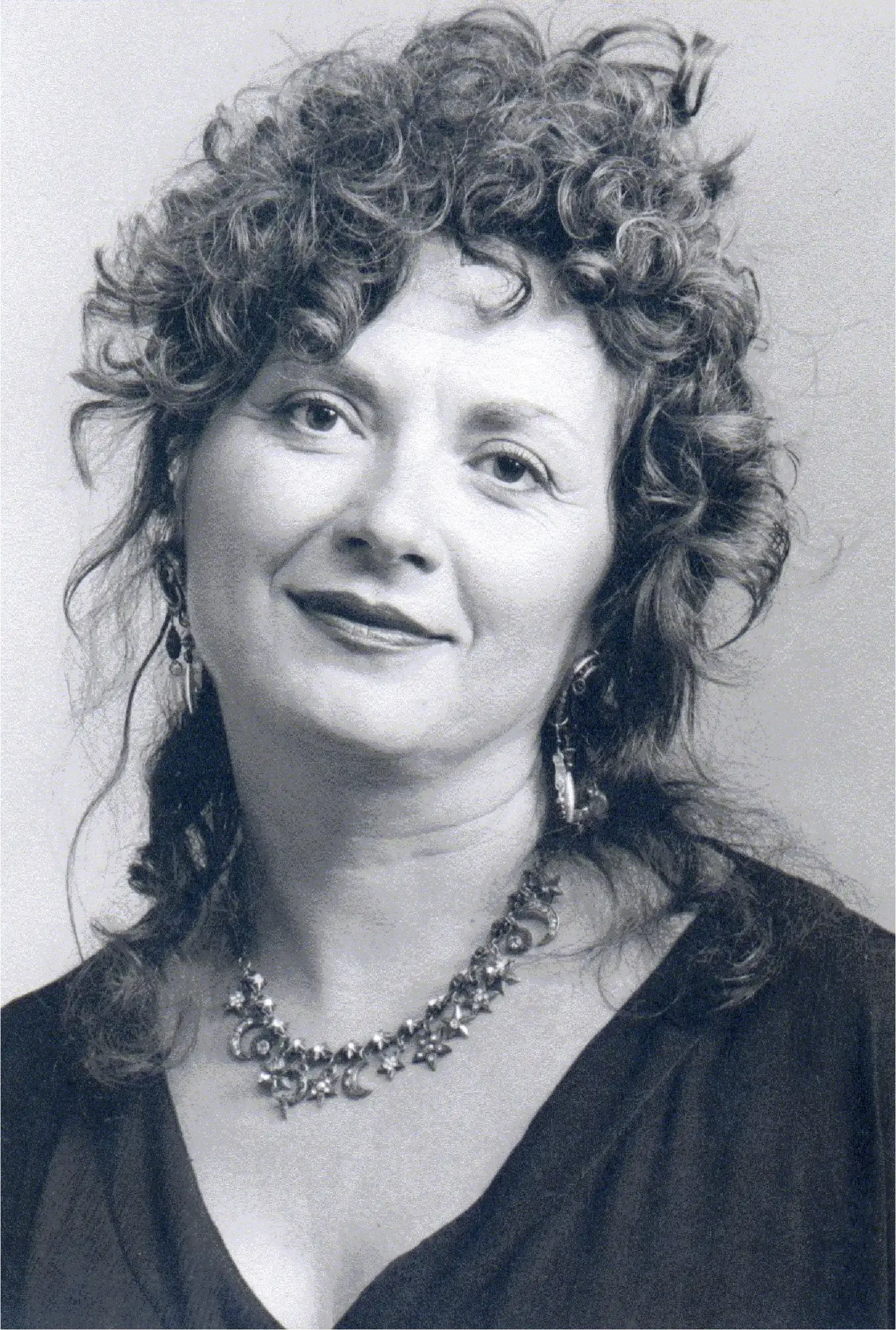 black and white image of woman with curly hair in half updo with necklace