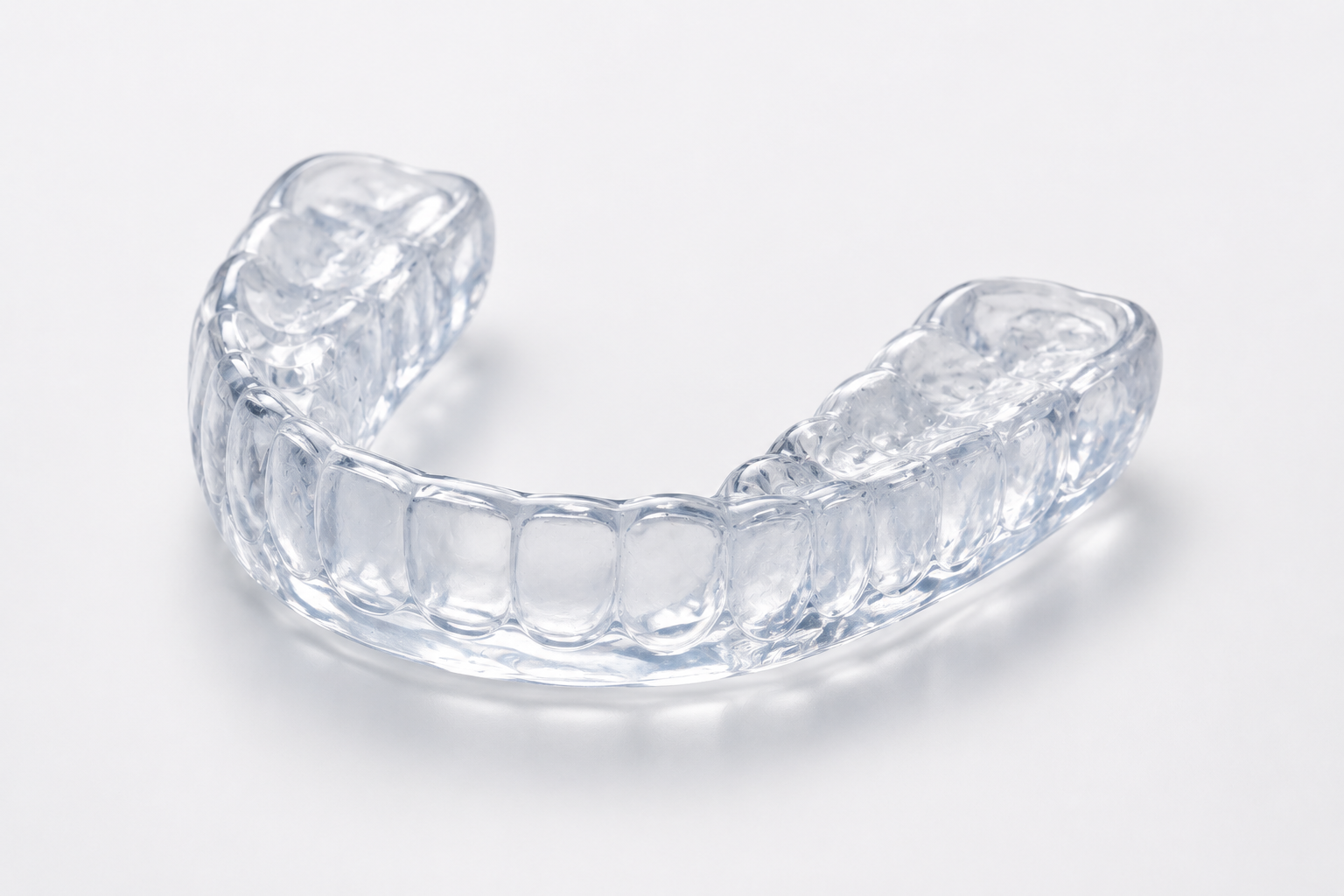 A clear plastic orthodontic aligner on a white surface.