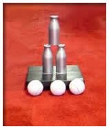 Three white spherical objects on a black platform, with two silver cylindrical objects balanced vertically and one smaller silver cylinder on top, all on a red background.