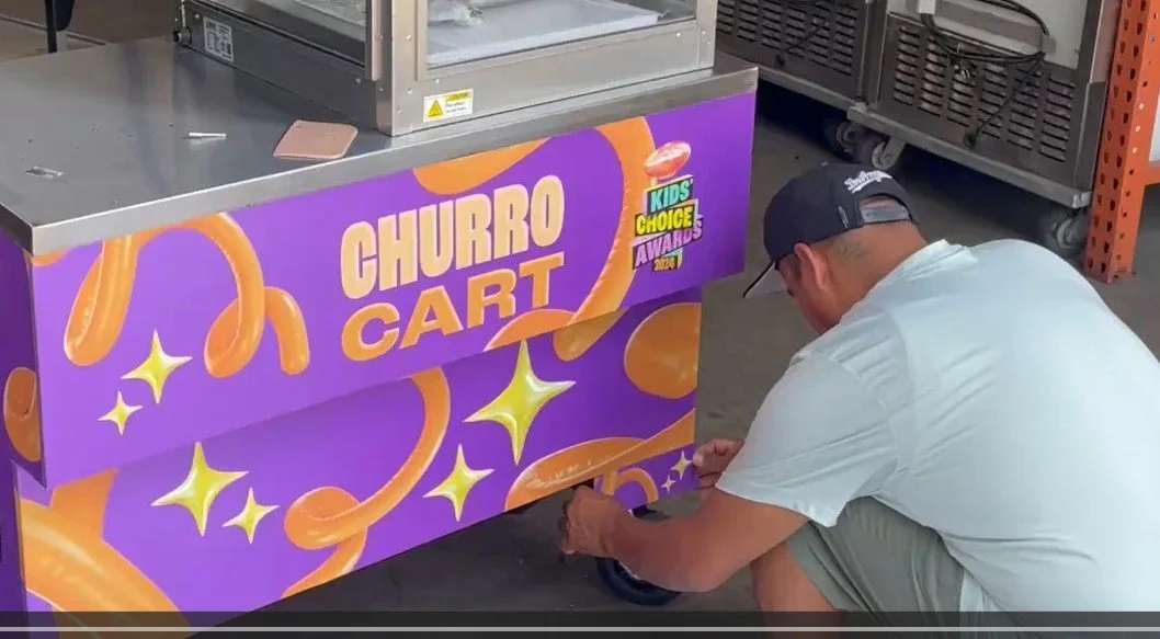 A Barts Carts staff applying a customer Nikeleoden branding to our churro carts