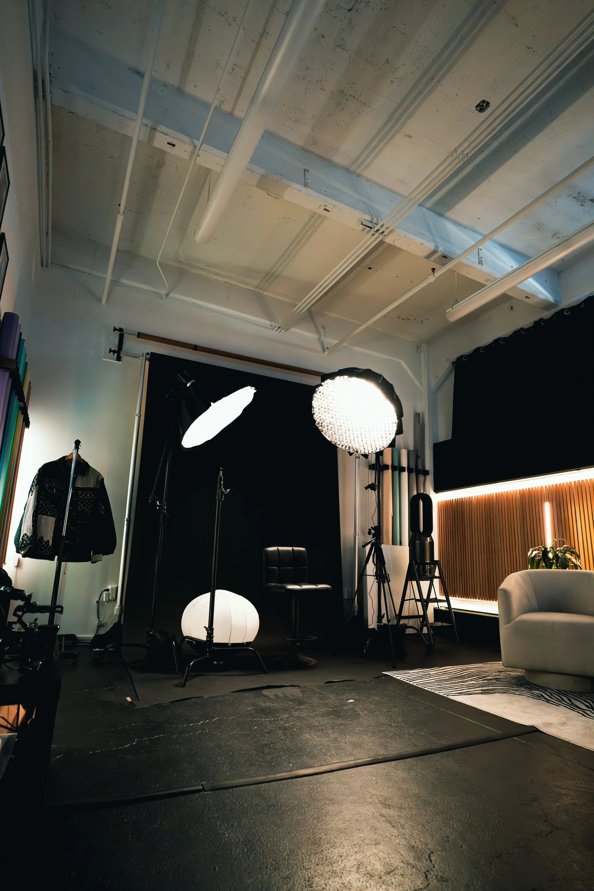 Photography studio with photography equipment, lights, backdrop, and furniture, set up for a photoshoot.