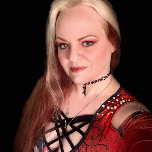 A woman with light blonde and reddish hair, wearing red eyeshadow, black choker, and red top with black lace and pearl details, posing against a black background.