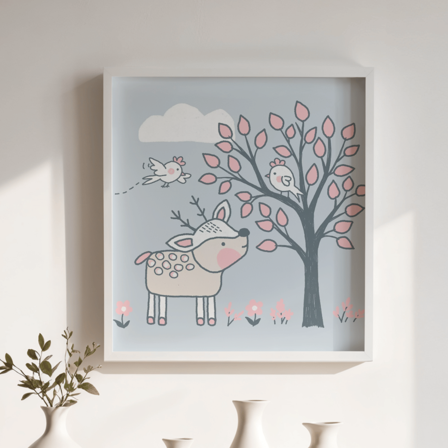 Decorative framed wall art featuring a whimsical illustration of a deer with pink cheeks, a tree with pink leaves, a flying bird, clouds, and flowers at the bottom in soft pastel colors.