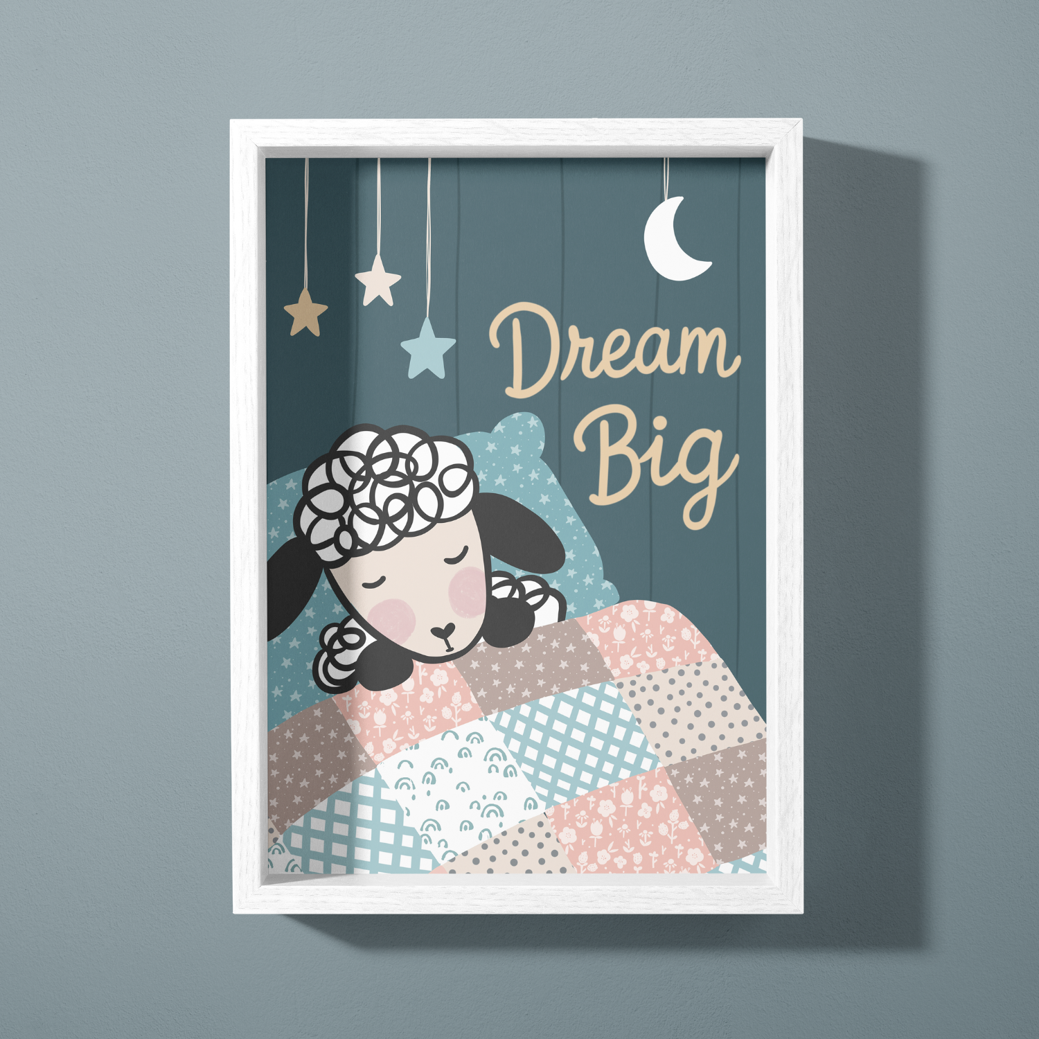 A framed artwork with the phrase 'Dream Big', featuring a sheep sleeping under a starry sky with hanging stars and a moon, and a patchwork quilt.