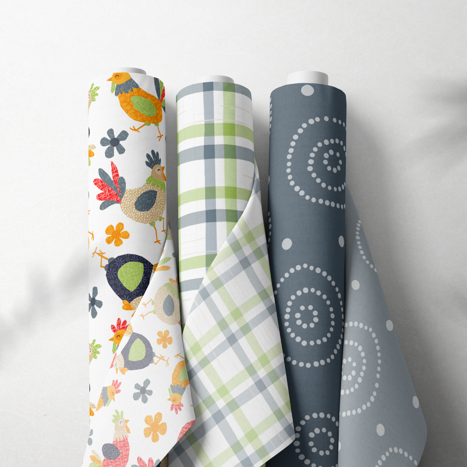Four rolls of patterned wrapping paper standing upright on a white surface, featuring colorful designs including birds, flowers, plaid, and spirals.