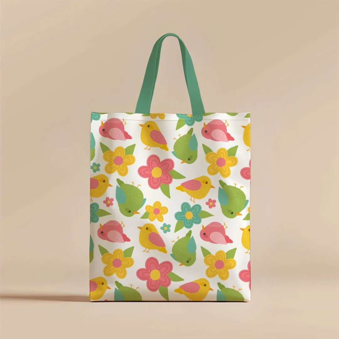 White shopping bag with colorful bird and flower pattern, green handles, on a beige background.