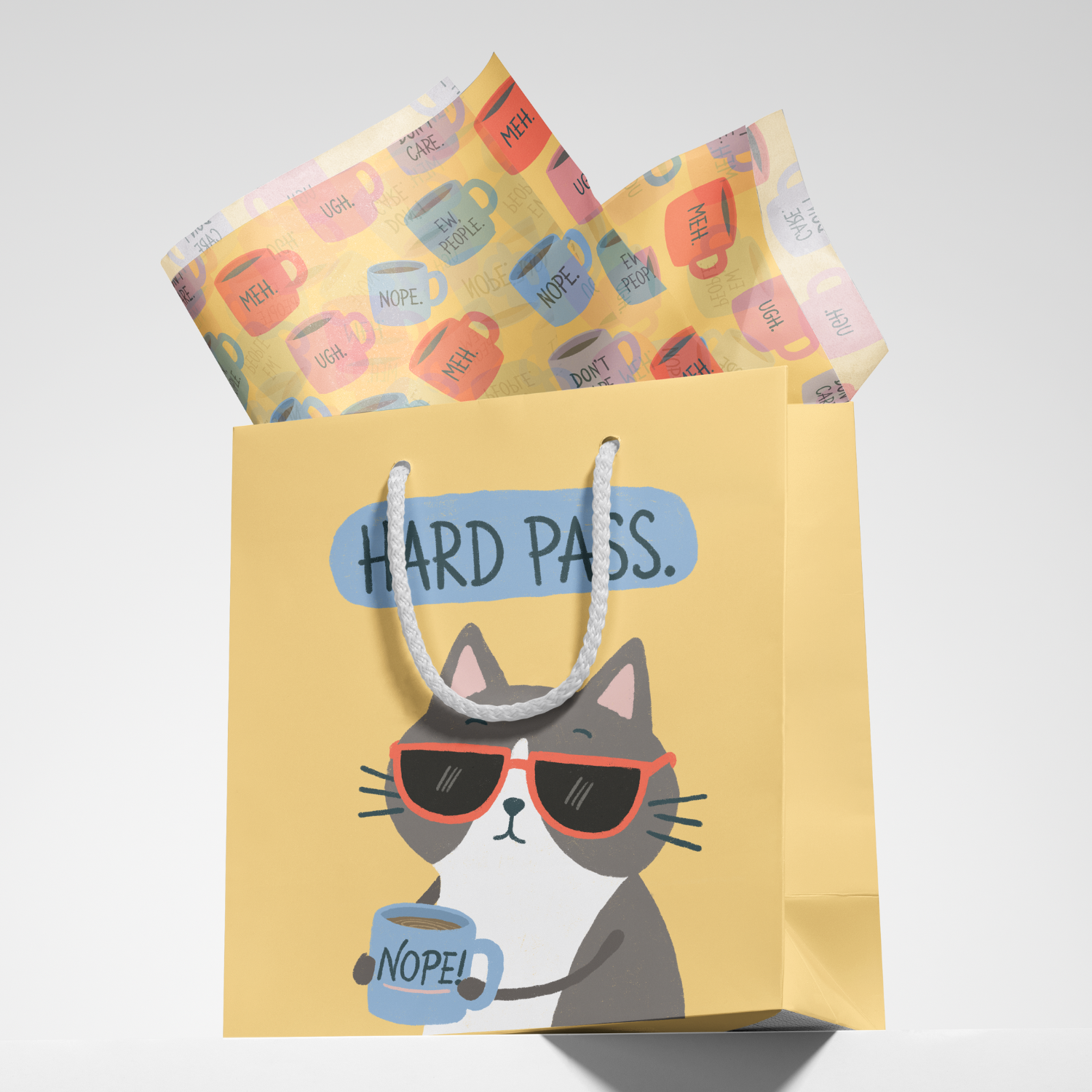 A yellow paper gift bag with a cartoon cat wearing sunglasses, holding a coffee mug labeled 'NOPE!'. The bag has a label 'HARD PASS.' and features colorful coffee mugs with humorous phrases like 'UGH!', 'MEH.', 'NOPE.', and 'EW.PEOPLE.' inside the bag.