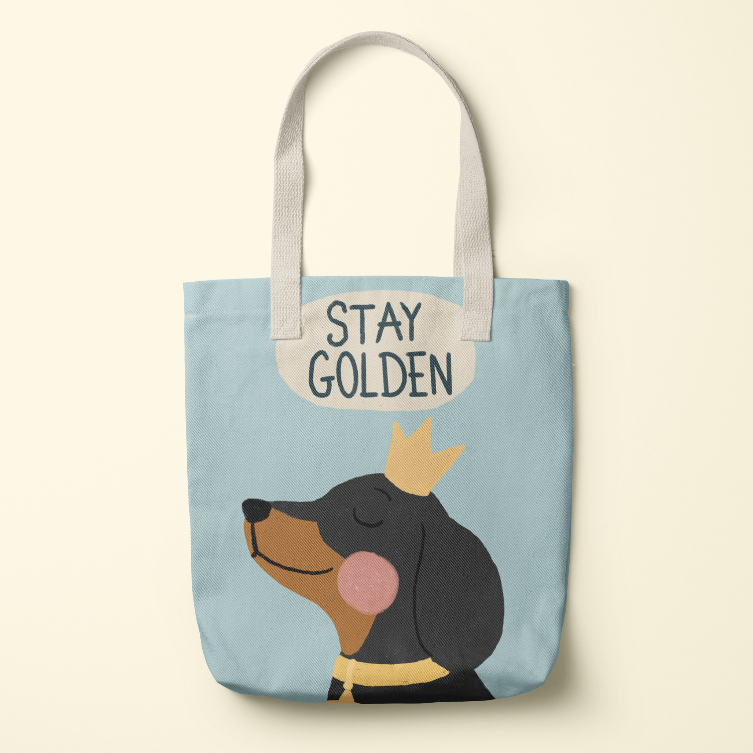 A tote bag with a cartoon illustration of a happy dog wearing a crown, and the phrase "Stay Golden" inside a speech bubble above its head.