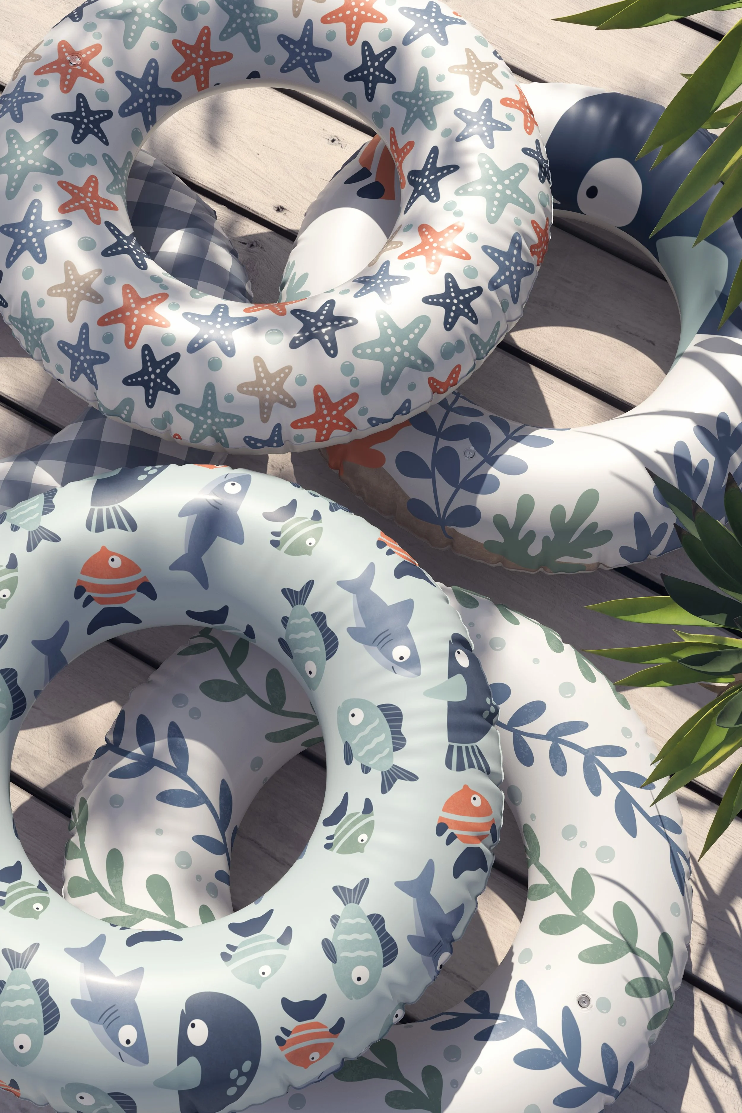 Inflatable floaties with fish, starfish, and sea creatures nautical patterns, on a wooden surface with green plant leaves.