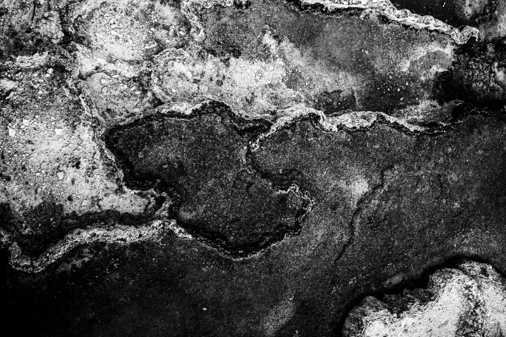 Close-up of rocks and soil in black and white, showing rough textures and irregular shapes.