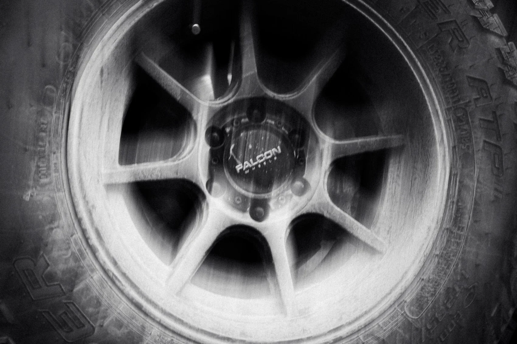 Close-up of a Falcon wheel rim on a tire, black and white photograph.