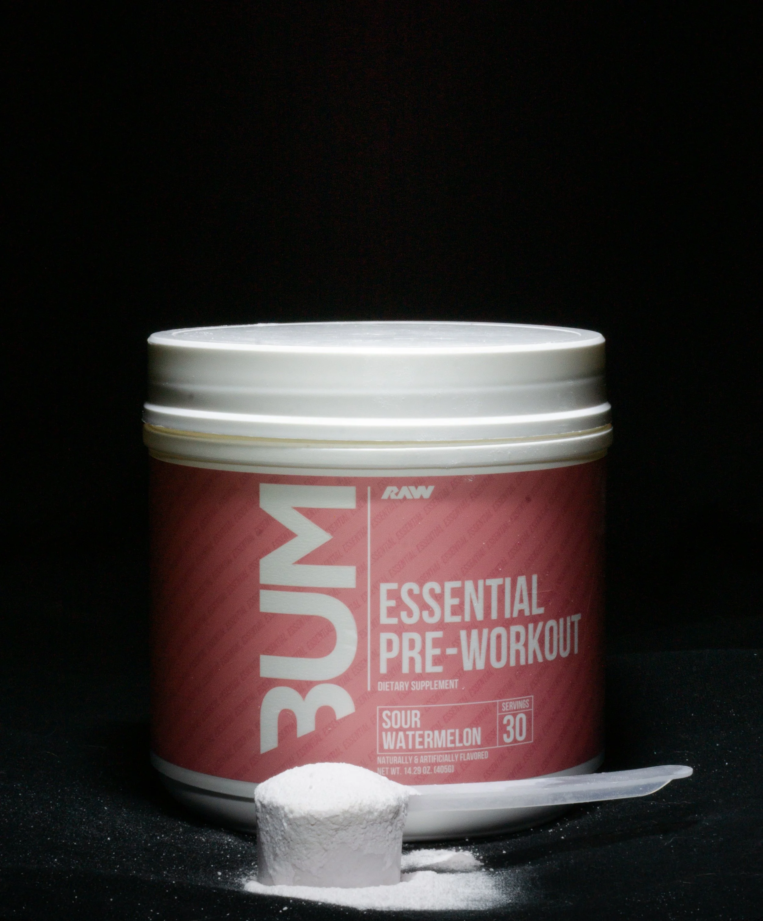 Close-up of a container labeled essential pre-workout supplement with a scoop of white powder in front, against a black background.