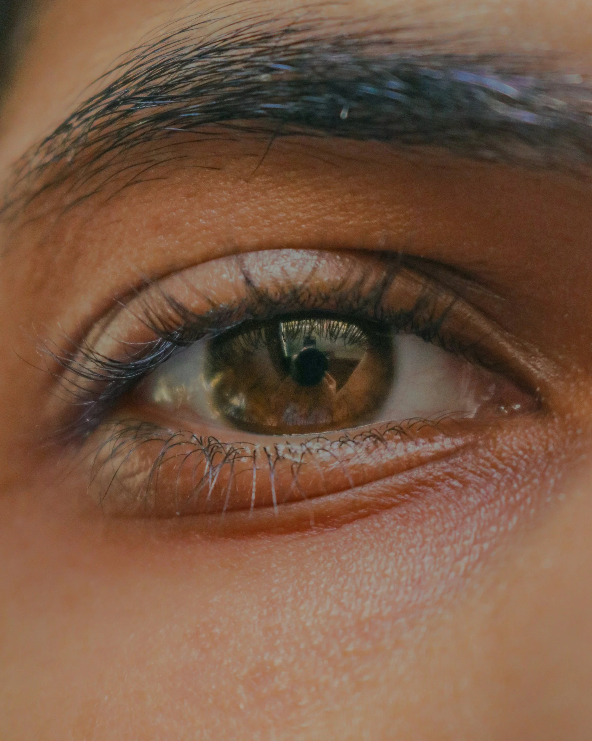 Close-up of a human eye showing the iris, pupil, eyelashes, and surrounding skin.
