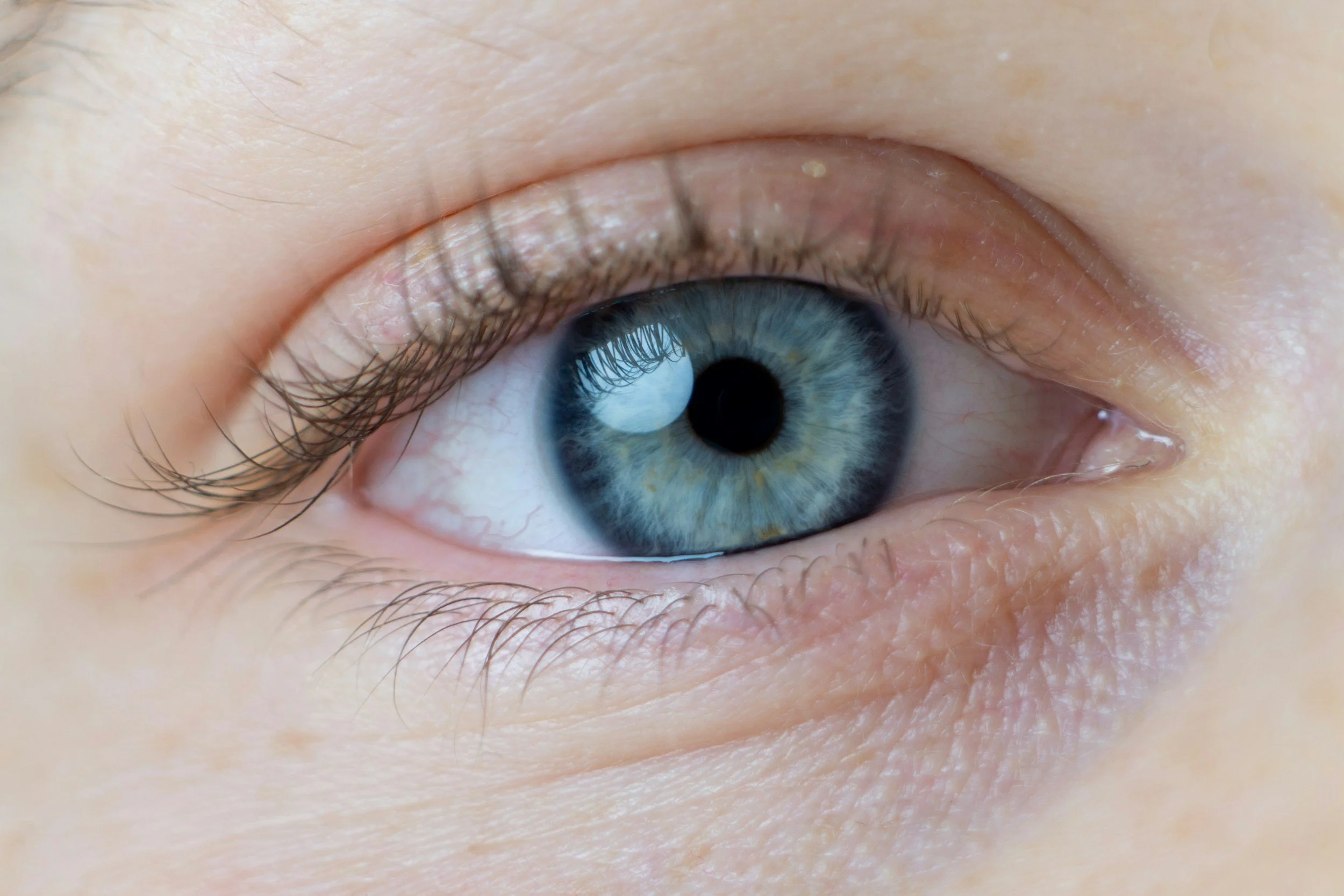Close-up of a human eye with a blue iris and surrounding skin.