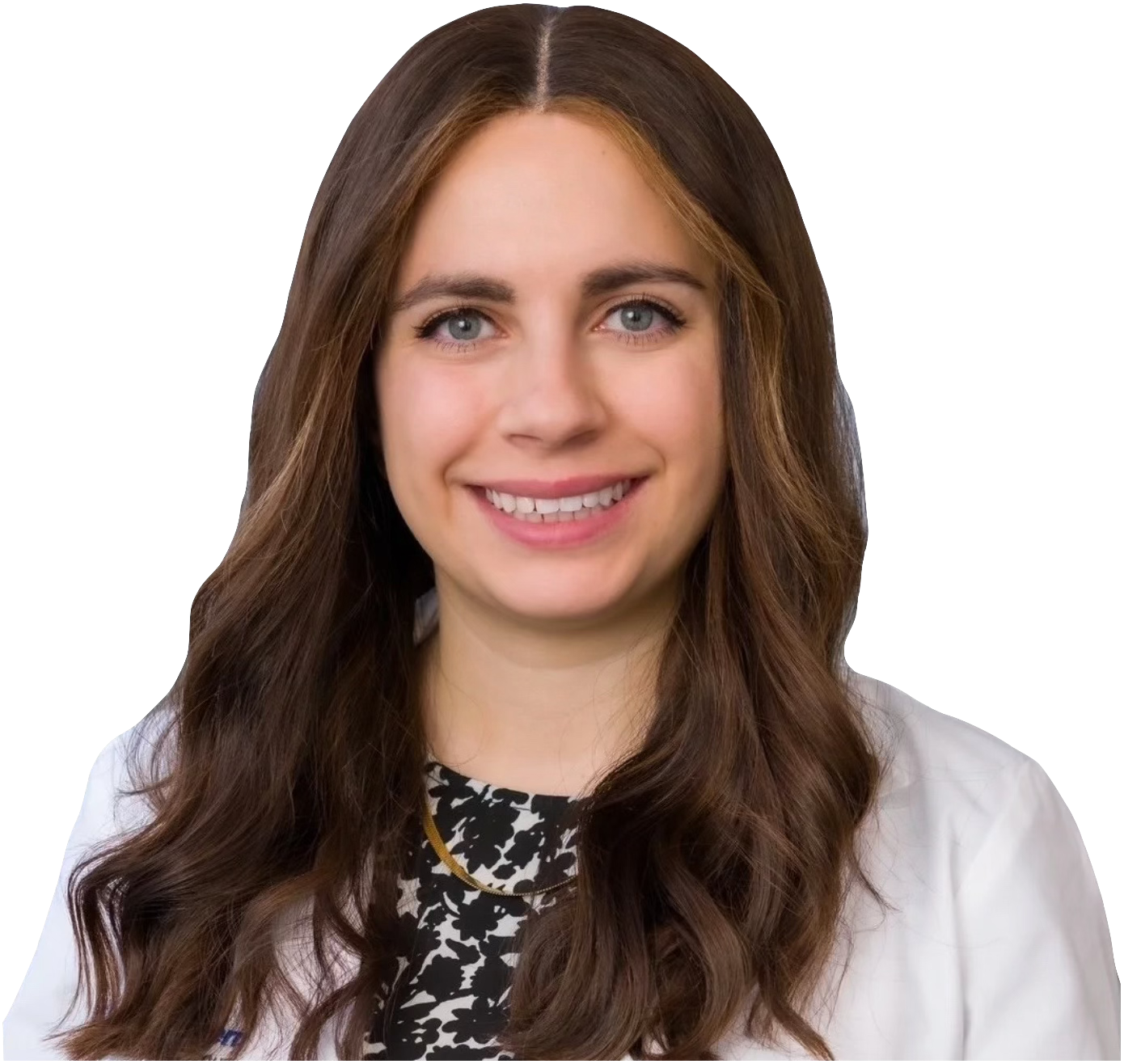 A young woman with long brown hair and blue eyes smiling, wearing a white coat and a black and white patterned top.