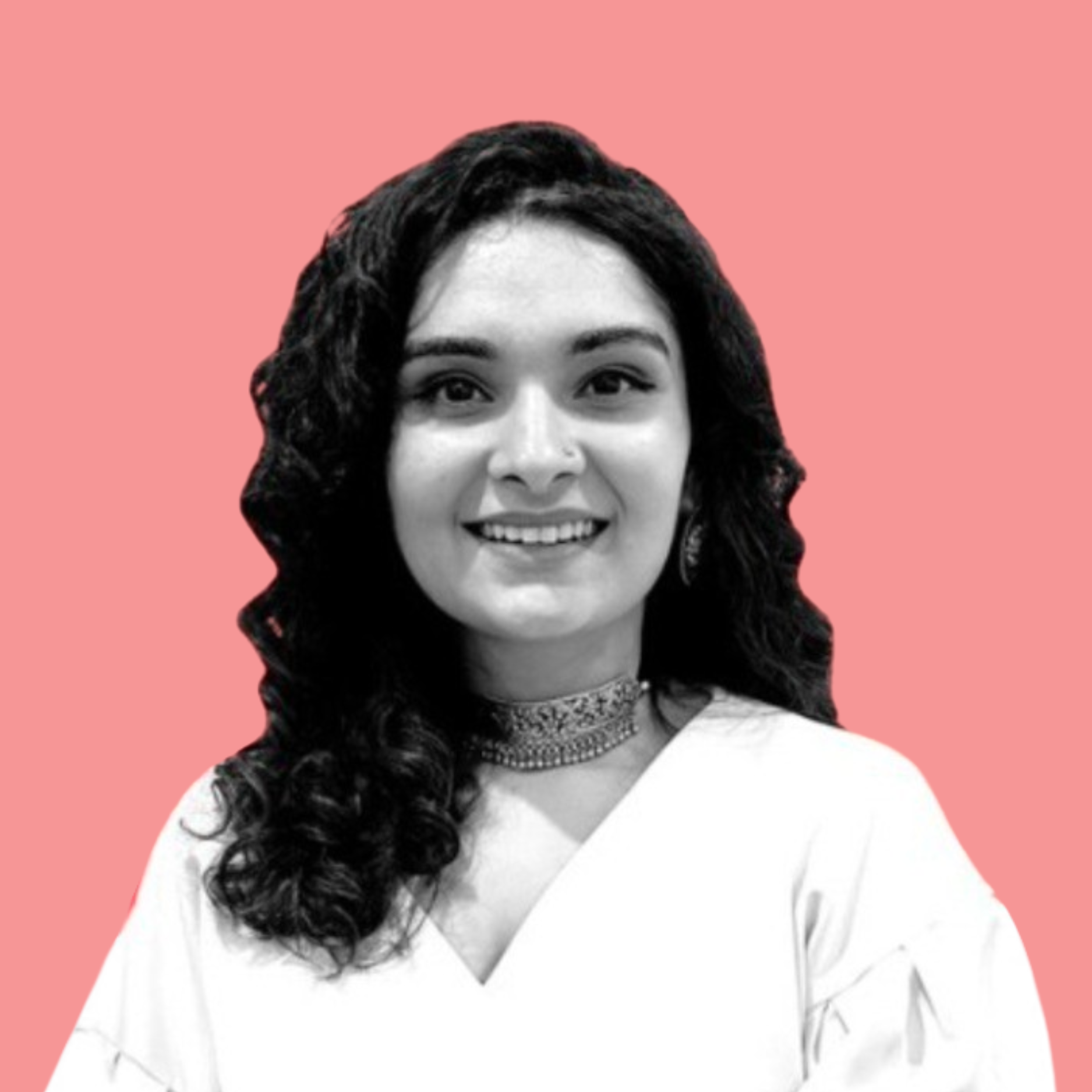 Black and white portrait of a smiling woman with long curly hair wearing a white top and a necklace, against a pink background.