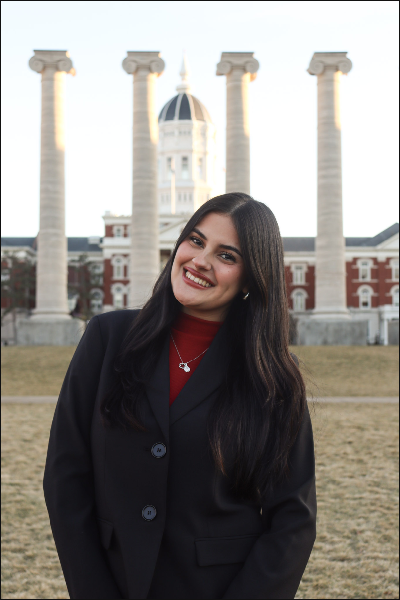 Young woman smiling in front of a historic building with columns and a dome.