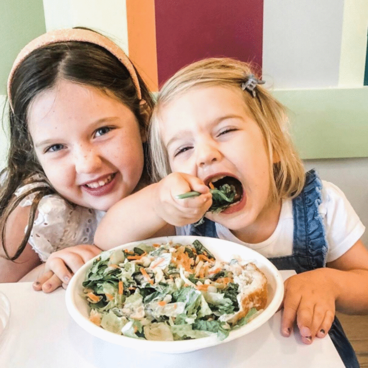 Two young girls enjoying a fresh salad at Verde, promoting $3 Kids' Meals on Weekends for healthy dining experiences.
