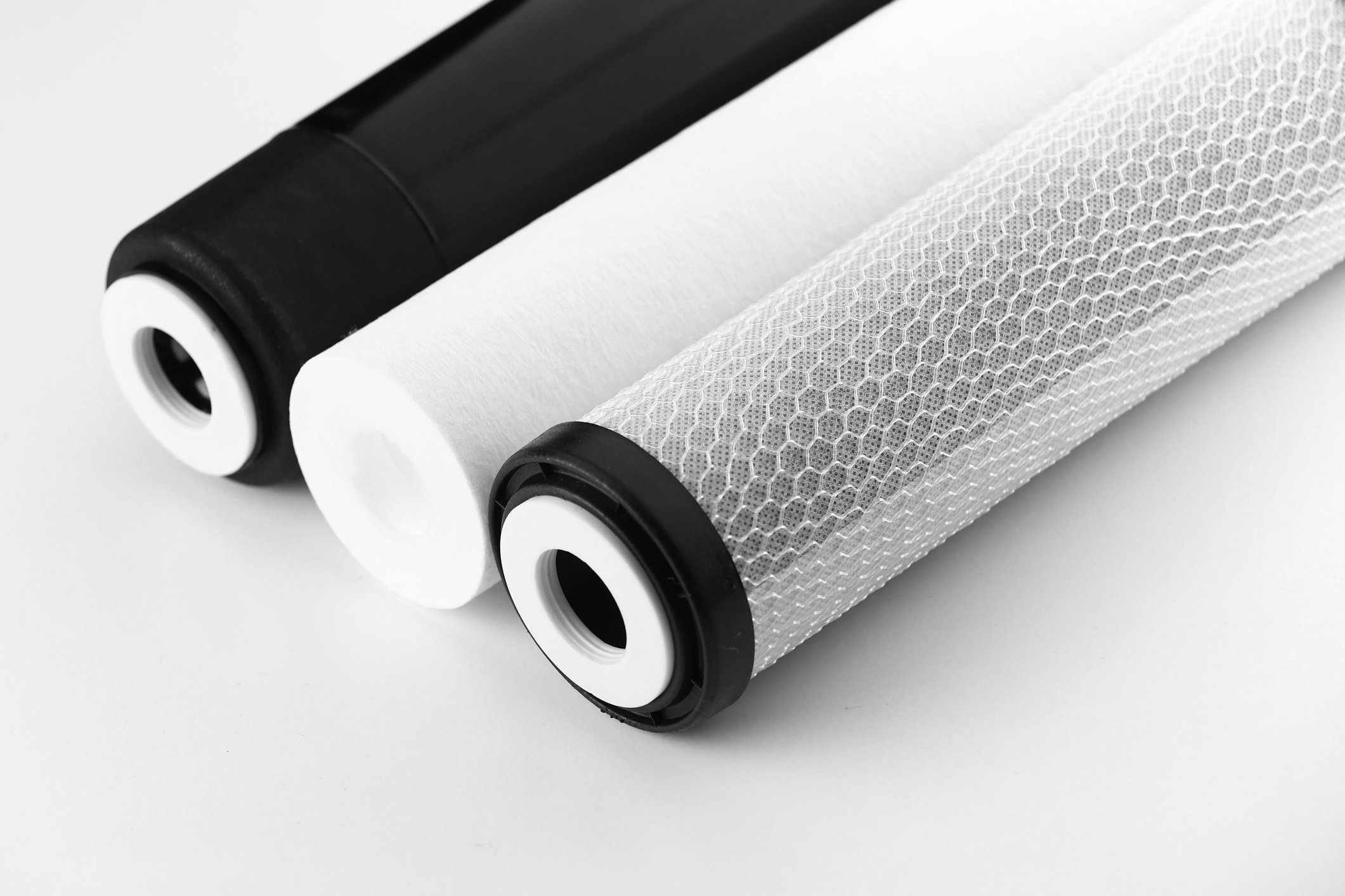 Close-up of two water filter cartridges, one black and one white, with a honeycomb pattern on the white cartridge, set against a plain white background.