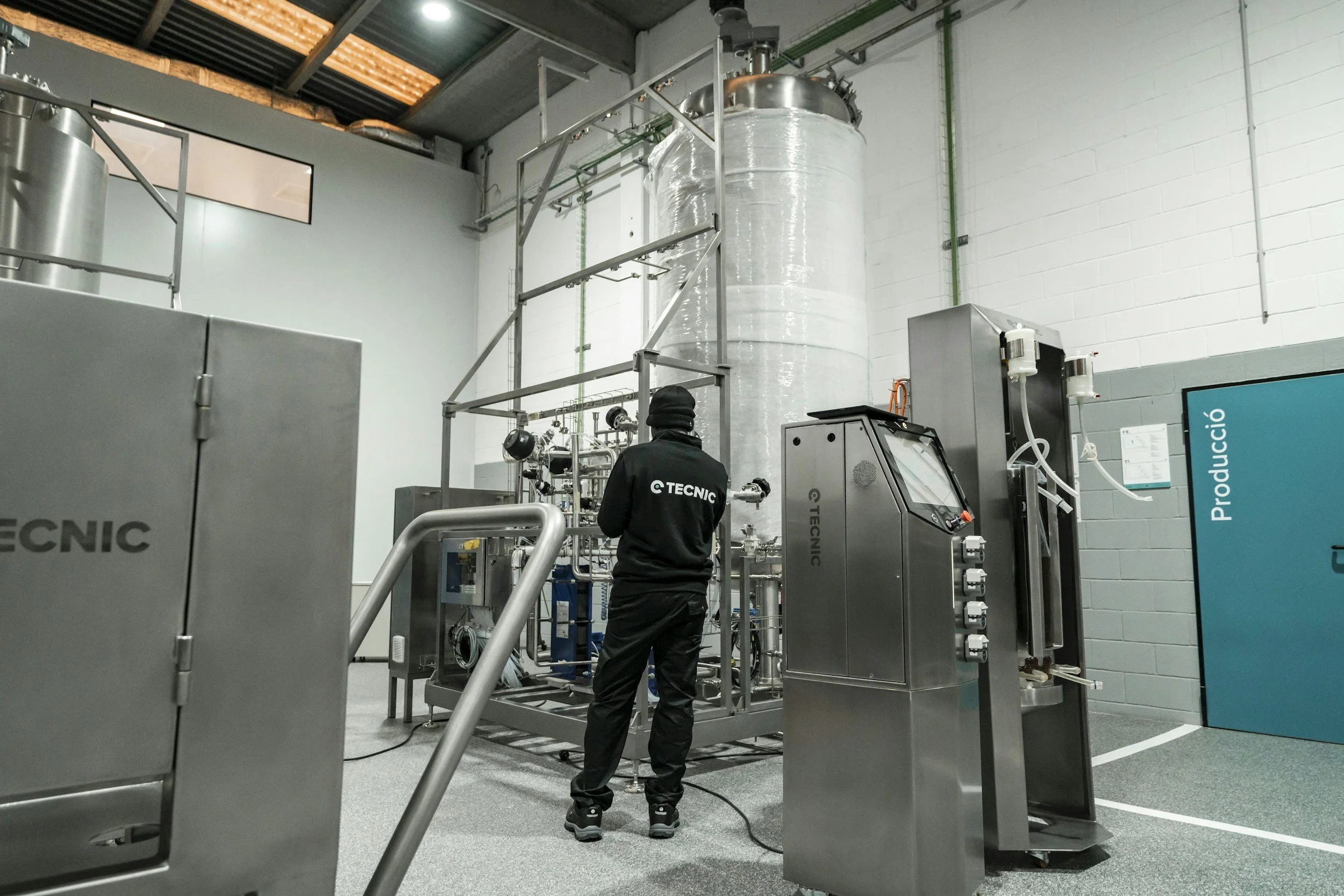 Technician in a chemical processing facility with the Tecnic logo working with industrial machinery.