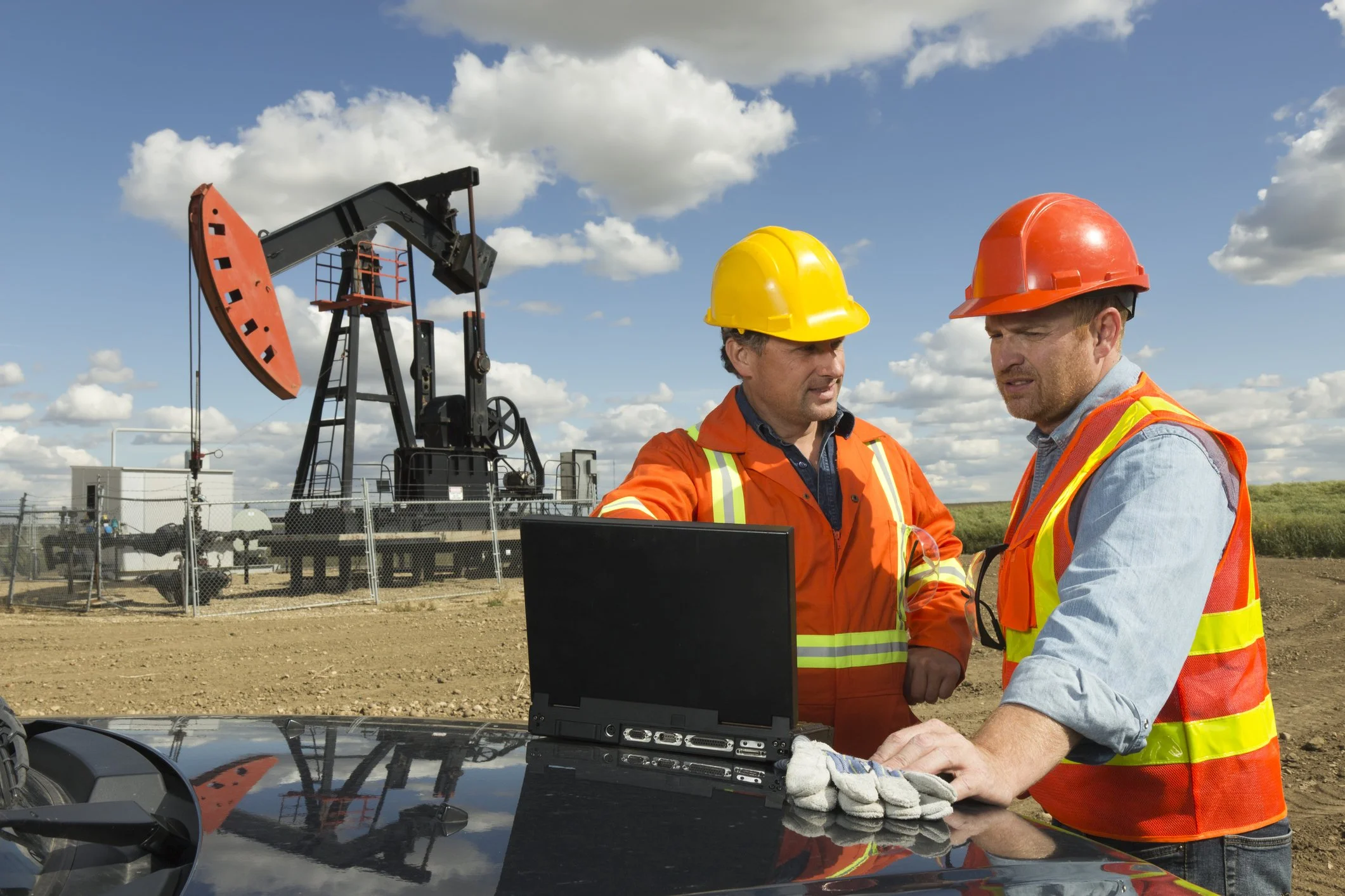 Two people at an pump jack working on a scenario.