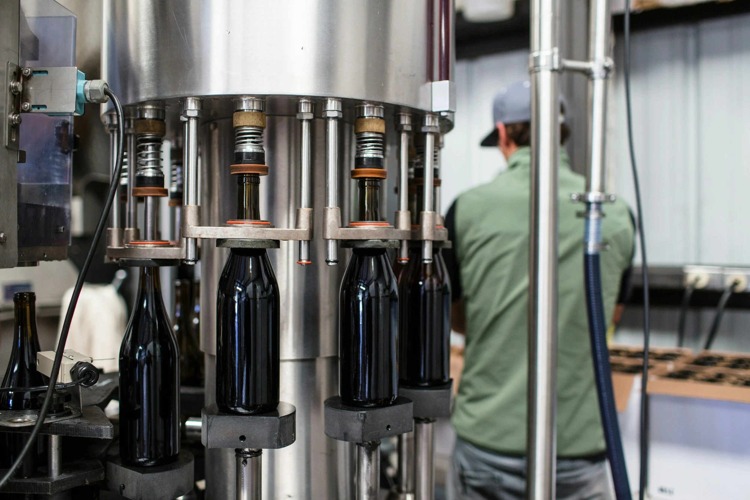 A worker operating bottling machinery in a bottling facility in the Mountain West.