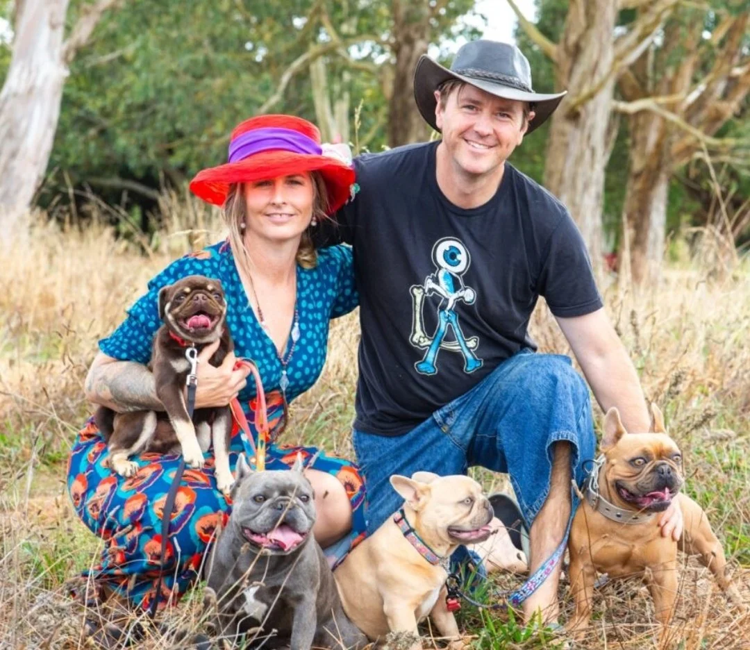 Alistair and Olivia Potter of Le Epitome Kennels in Waikato, New Zealand, pictured outdoors with Eden, Pluto, and Mickey, three coloured French Bulldogs, alongside Tim Tam, a chocolate coloured Pug stud dog.