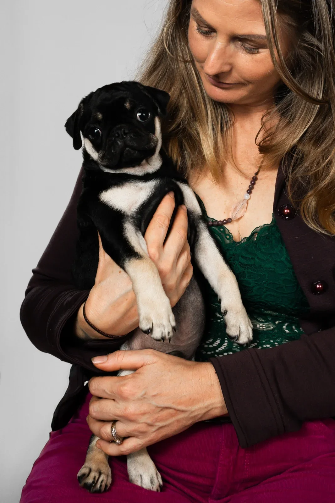 Woman holding a black-and-tan Pug puppy raised by Le Epitome Kennels.