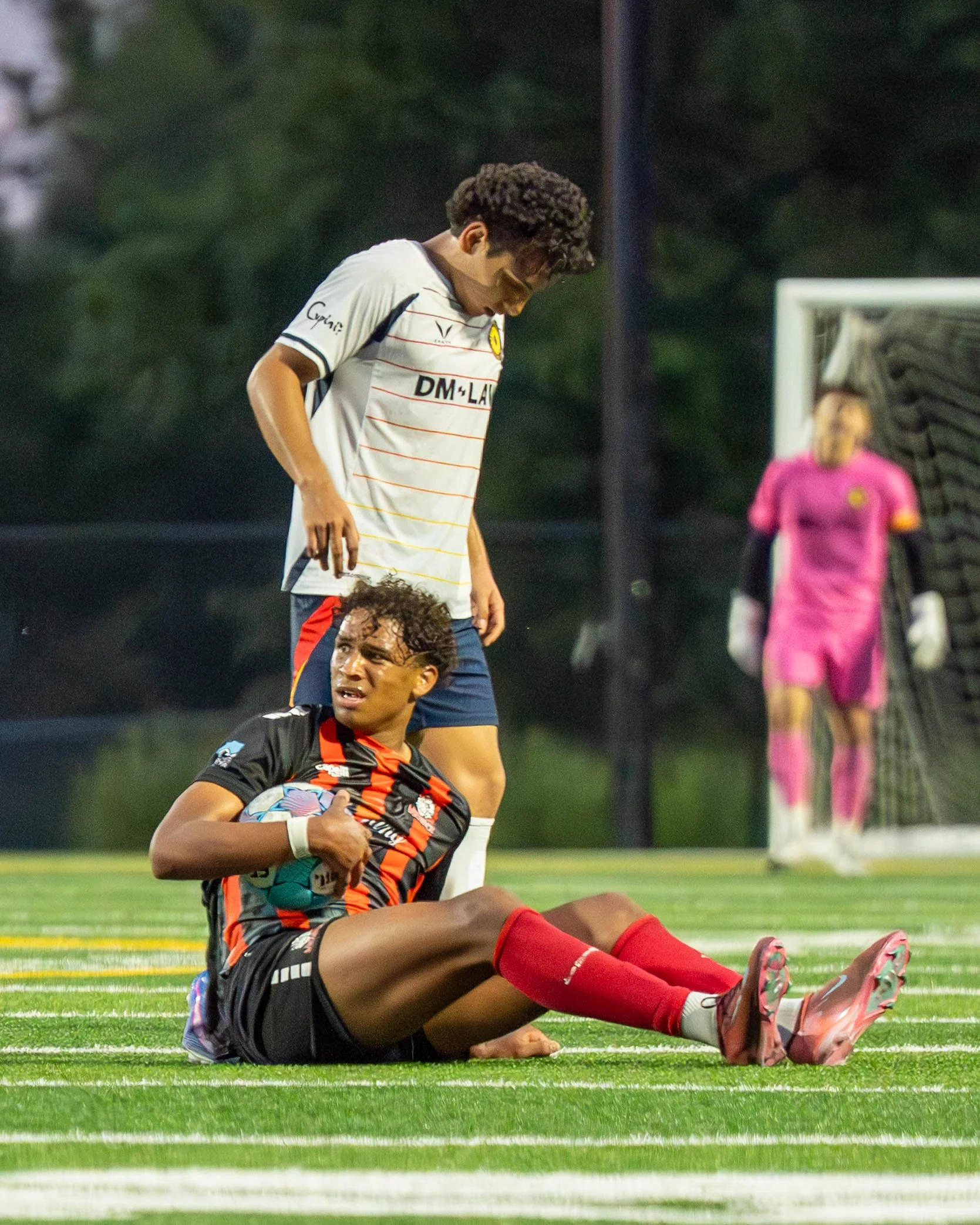 Des Moines Menace player on the ground holding the ball after being fouled by an opponent standing right behind him at home against Sunflower State FC on May 30th, 2026 - Photo by: Austin Farrow