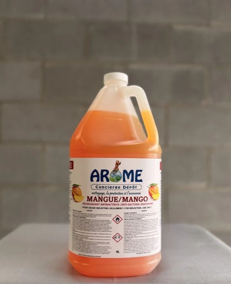 A large 4-liter bottle of antibacterial disinfectant with a peach scent, labeled in French, placed on a white surface against a gray tiled wall.