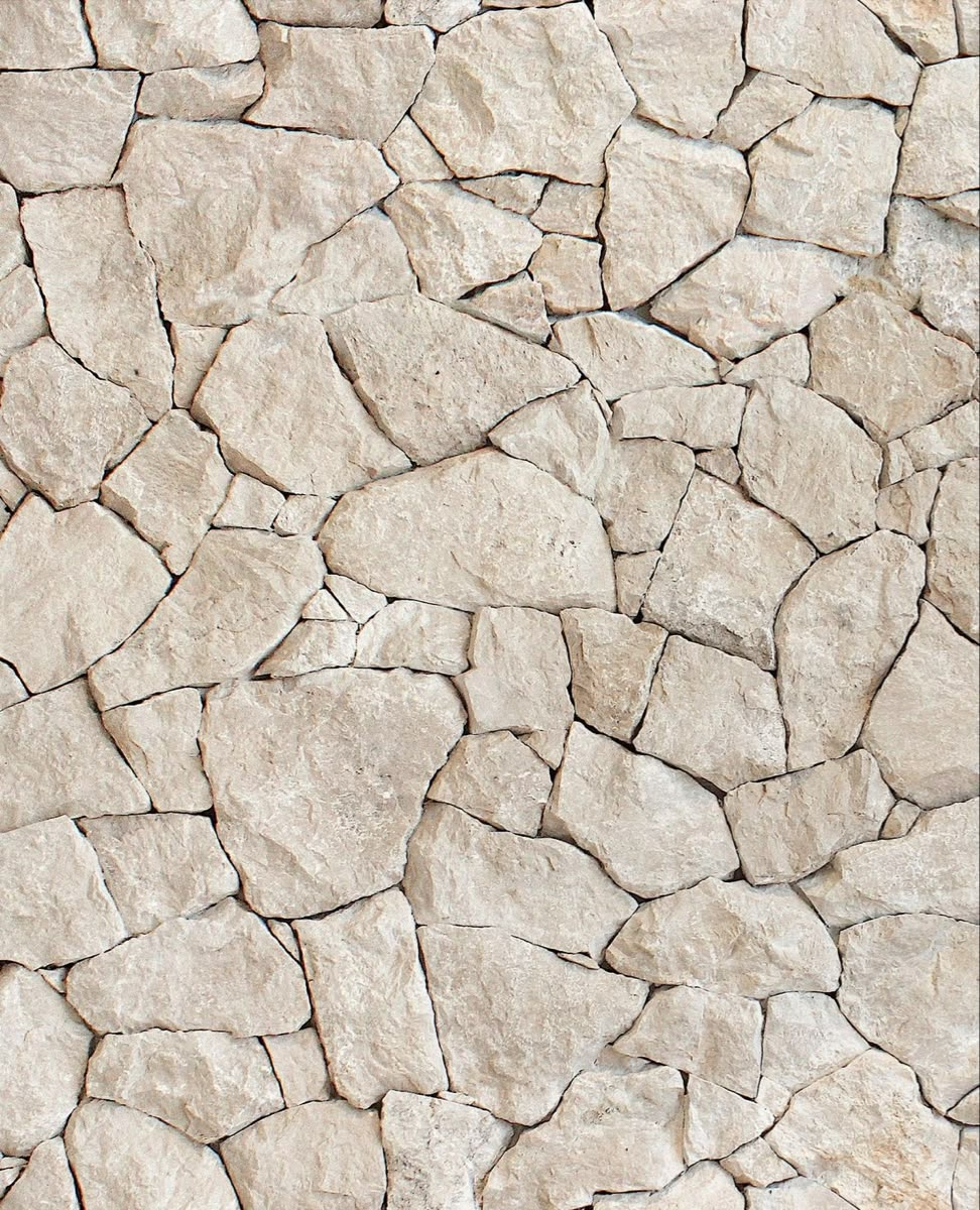 Close-up of a wall made of irregularly shaped beige stones fitted together.