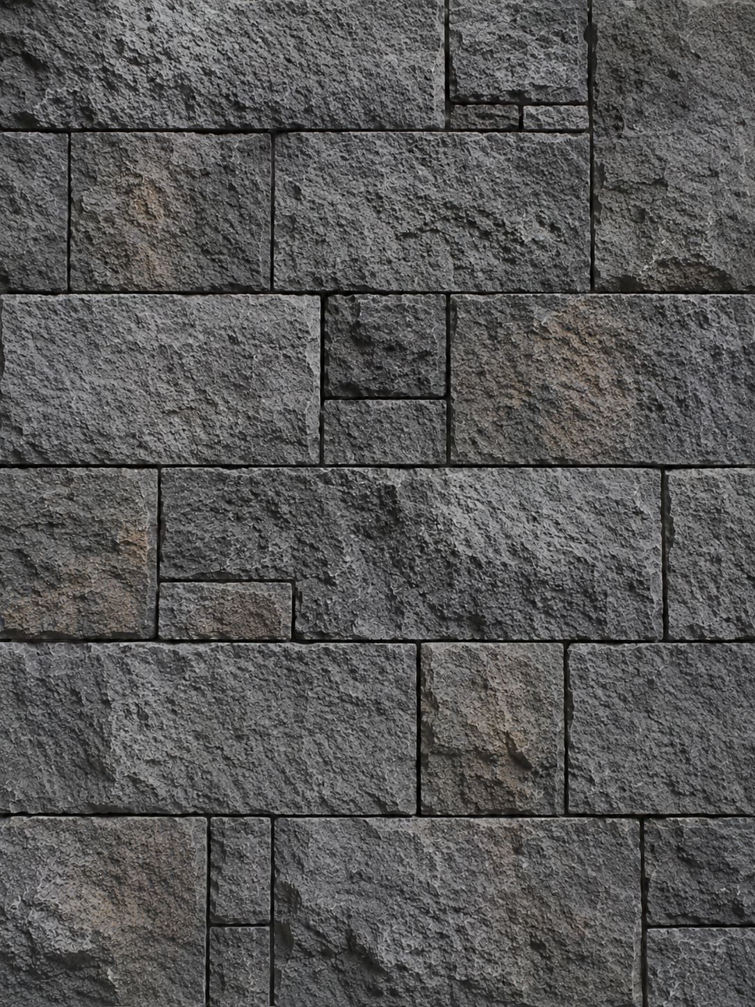 Close-up of a textured gray stone brick wall with rectangular blocks.