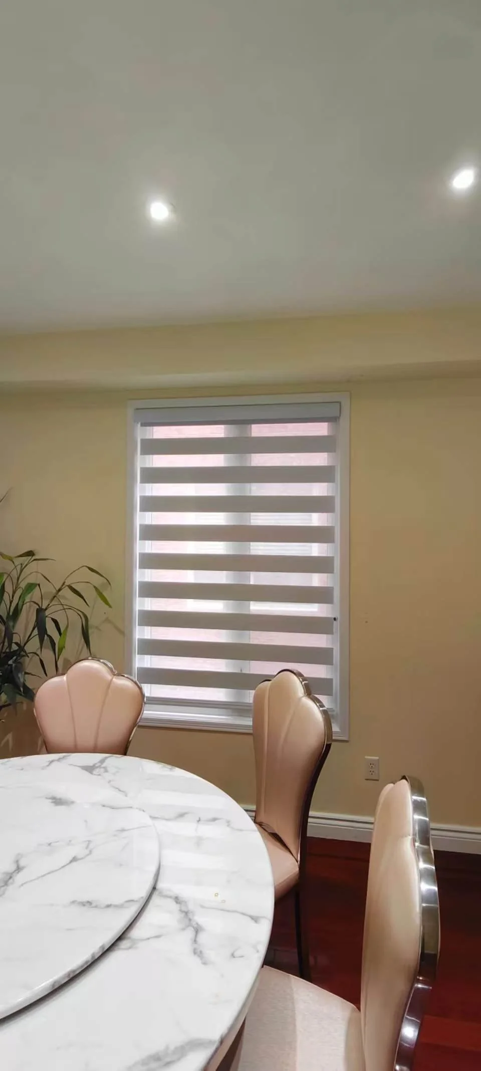 A dining room with a elegant zebra blind which can adjust sunlight and make privacy for the family