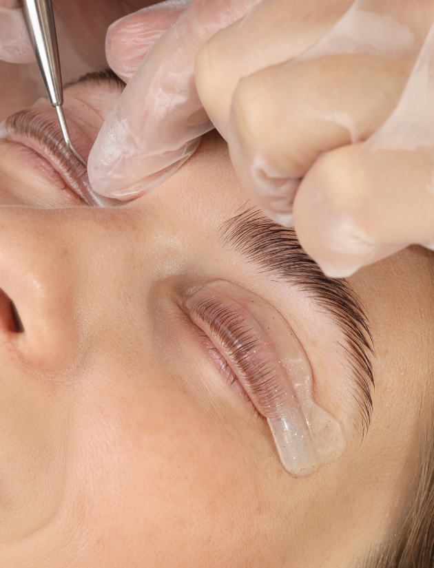 Close-up of a person receiving a cosmetic procedure under the eye, with a healthcare professional wearing gloves using a small tool near the eye.