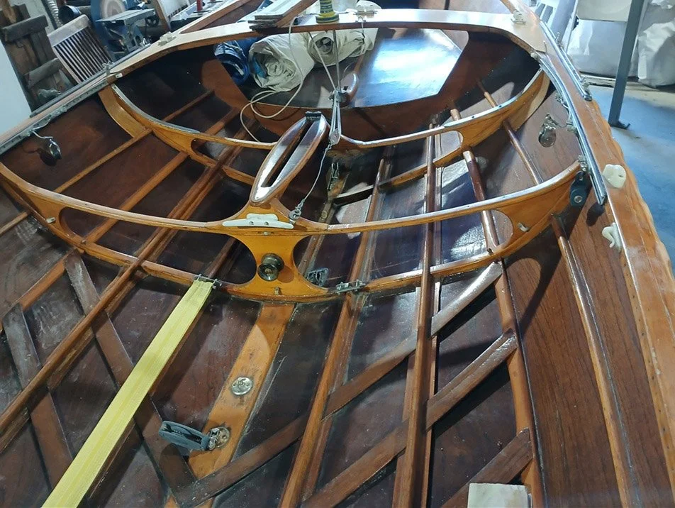 Interior of 16ft skiff 'Michelle' under renovation, showing wooden ribs, frame, and tools inside a workshop.