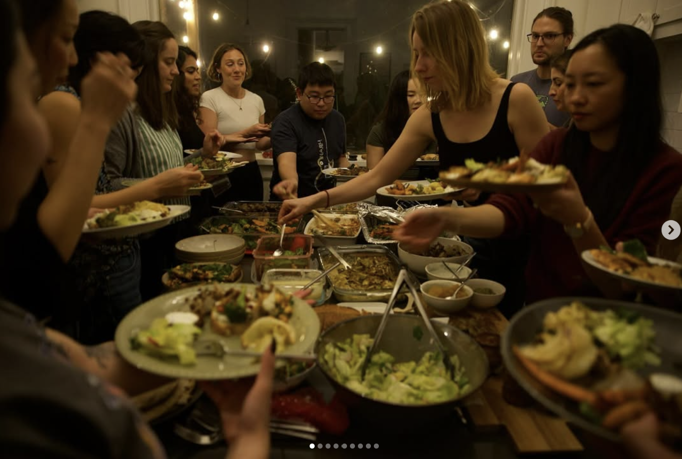 People gathered around a table enjoying a buffet-style meal with various dishes.