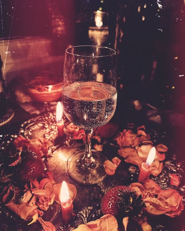 A glass of sparkling water on a decorated table with roses and candles.